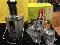 Juice Bullet juicer and two plastic pitchers with original box behind
