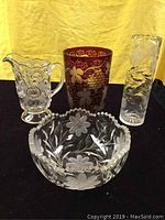 Photo showing all four glass pieces together: etched crystal bowl, red glass vase, clear etched vase, and pressed glass pitcher.