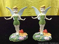 Front view of two Royal Doulton Disney Tinkerbell figurines standing on floral and mushroom decorated bases.