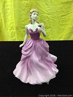Front view of the Royal Doulton Victoria figurine, showing detailed purple gown and flower in hand.