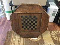 Octagonal wooden game board, side showing checkerboard pattern with alternating dark and light squares and surrounding wooden frame with signs of wear.