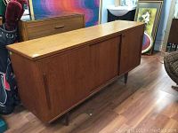 Front view of teak sideboard showing two sliding doors and tapered legs