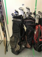 View of the two golf bags, Dunlop and Wilson Prostaff, showing multiple golf clubs inside and wear on bags.