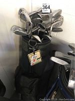 Full view of green Dunlop golf bag filled with many assorted golf clubs showing wear