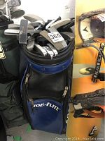 Blue and black Top Flite golf bag with multiple golf clubs stacked inside showing wear and use.