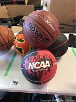 View of the 4 basketballs on table including Wilson X-Connect, flame decorated balls, and classic brown basketballs