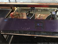 Photo of one of the HG152 snowboards showing the dark base with visible scratches, scuffs, and black bindings attached.