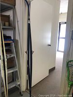 Full view of two blue Karhu cross country skis standing upright against a wall near a door, showing their full length.