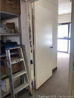 Photo showing pair of Atomic cross country skis propped against a wall and a door in an indoor setting, with visible wear on skis.