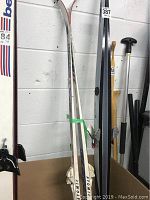 Pair of Atomic cross country skis and Swix poles against a wall, skis measure 71 inches.