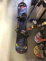 Top view of the Concon Surf snowboard laying on the floor with bindings attached and visible wear.