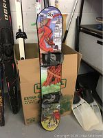 Full view of Echos Extreme 130 snowboard with colorful dragon and castle graphic, showing wear and attached bindings.