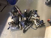 Three pairs of rollerblades of different brands and sizes arranged on concrete floor.