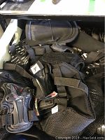 Collection of black sports pads with mesh and nylon construction, some with visible hard plastic guards and adjustable straps, arranged on a shelf showing wear.