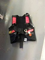 Scuba vest front view laid flat showing straps and inflator hose on floor.