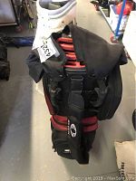 Front view of the EOS Sports golf bag showing black and red color with wear and multiple compartments.
