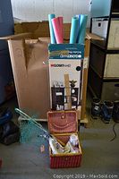 Photo showing fishing net, two fishing rods in a wicker basket, box with swim noodles.