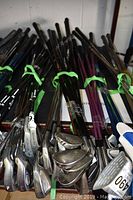 Overview of the 12 junior golf clubs with metal shafts and various heads, some with purple and black shafts, shown in a pile with visible wear on club heads and shafts.