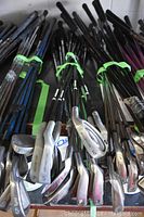 Full view of 12 adult golf clubs featuring various heads and shafts stacked together showing some use.