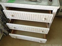 Close-up view of the dresser drawers open showing wicker construction and knobs