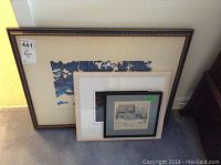 Three framed prints shown together leaning against the wall on carpeted floor.