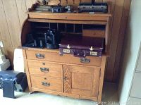 Full view of oak roll top desk showing the top open workspace area with pigeonholes, a closed briefcase, and kitchen appliances on top.