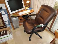 Computer desk with woodgrain surface and metal frame, including keyboard tray. The desk has a computer monitor on it (excluded from sale) and a small working desk lamp at the corner.