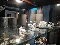 Display shelf with assorted Swarovski crystal figures and original boxes in the background. Figures include turtle, frog, hedgehog, and swan.