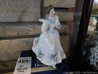 Photo showing the full front view of the Royal Doulton figurine, highlighting the painted blue flowers on the dress and the seated woman figure.
