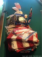 Pile of paddles, flags, disc golf disc, knives, leather goods on a pool table