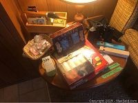 Overall lot on round table showing Rummoli game kit, poker chips, cards, and binoculars.