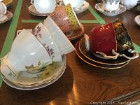 Photo showing six of the teacups stacked in sets on a table with visible detail on patterns and colors.