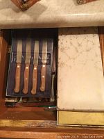 Drawer with blue case containing five J.A. Henckels Rostfrei steak knives with wood handles