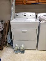 Front view of white Kenmore dryer with closed door, positioned next to a washing machine.