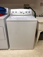 Front view of white Kenmore top loading washing machine, showing overall appliance shape and condition.