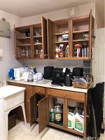 Full view of the cabinetry containing various cleaning supplies, glassware, and other items on shelves and countertop.