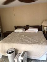 Full view of king size bed made up with bedding and pillows, carved wood headboard visible
