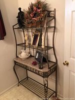 Full view of the metal bakers rack with marble top shelf and decorative various items on shelves removed for sale.