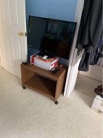 Sony 33-inch television on wooden media cart in room corner with some objects on cart shelf