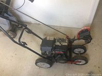 Full side view of Yard Machines gas edger showing frame, wheels, engine, and handle.