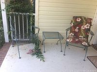 Porch rocker, chair with cushion, and small table on porch floor, angled view showing all three items.