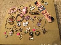 Photo showing entire lot of pink costume jewelry arranged on tan surface.
