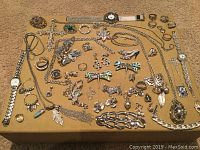 Photo showing various costume jewelry including necklaces, bracelets, rings, earrings, and watches laid flat on a surface.