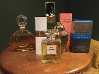 Group of six perfume bottles including Chanel N°19, Estee Lauder, David Beckham and others on a wooden surface