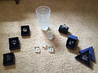 Overview photo showing all items in the lot, including the glass vase, multiple Swarovski crystal figurines and ornaments, some in blue boxes.