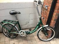 Side view of green Schwinn Loop folding bike with rear cargo rack and white fenders
