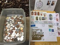 Photo showing a plastic container with assorted coins of various sizes and metals alongside a collection of stamps and first day covers on paper