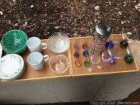 Wide view of all glassware and ceramic pieces arranged on a ledge outdoors showing variety and condition