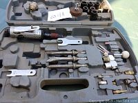Die grinder tool along with many grinding, sanding, and polishing attachments placed inside a molded grey plastic carrying case.