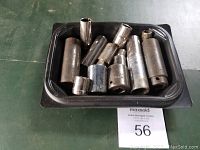 Tray holding 13 assorted metal sockets of varying sizes and lengths, used condition.